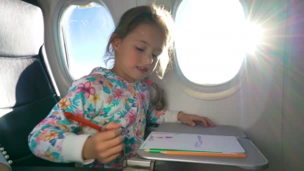 En lille pige rejser med et fly og tegner et billede med farverige blyanter . – Stock-video