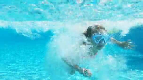 Kleines Mädchen mit Schnorchelmaske schwimmt unter Wasser im Pool. — Stockvideo