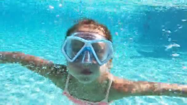 Malá dívka, která nosí maskou šnorchlování, plavání pod vodou v bazénu. — Stock video