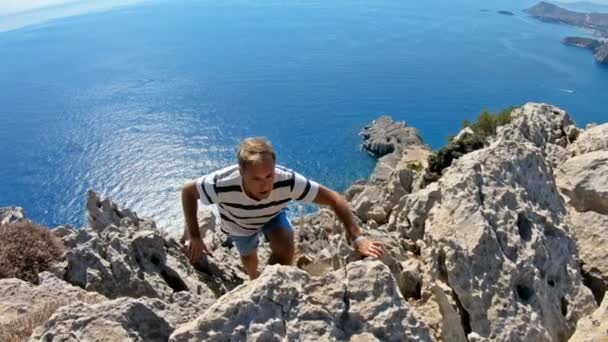 Junger Mann klettert auf die Spitze einer hohen Klippe. — Stockvideo