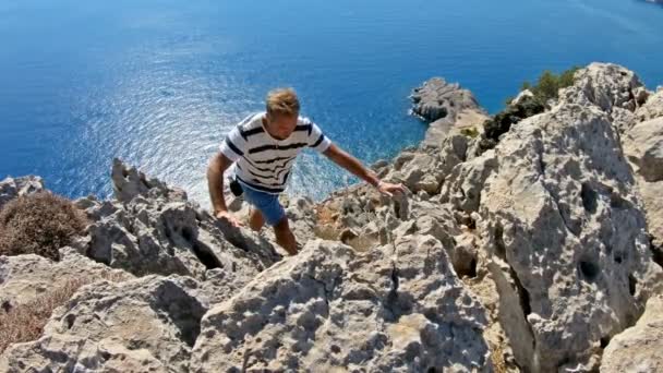 Junger Mann klettert auf die Spitze einer hohen Klippe. — Stockvideo