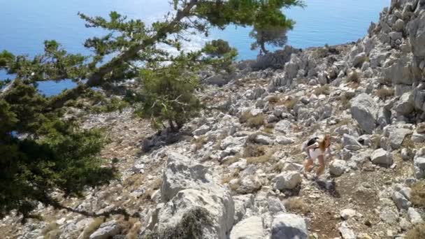 Ung kvinna klättrar en sten medan trekking utomhus — Stockvideo