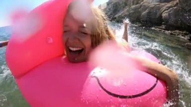 Denizin ve güneşin bir şişme Pembe Flamingo üzerinde yalan genç ince kadın seviyor