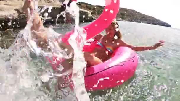 Jonge slanke vrouw geniet van de zee en de zon liggend op een opblaasbaar roze Flamingo — Stockvideo