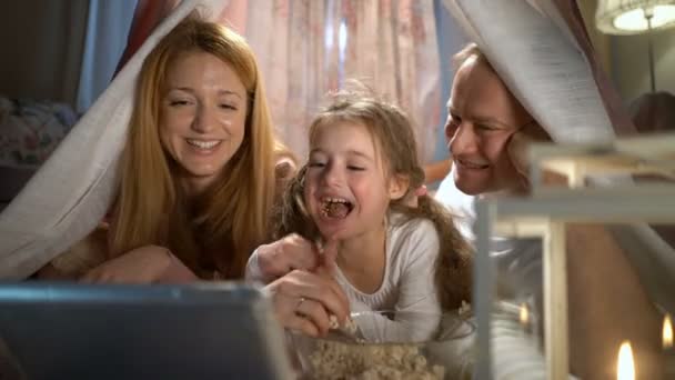 Klein meisje en haar ouders genieten van kijken cartoons online in de tent in de kinderkamer — Stockvideo