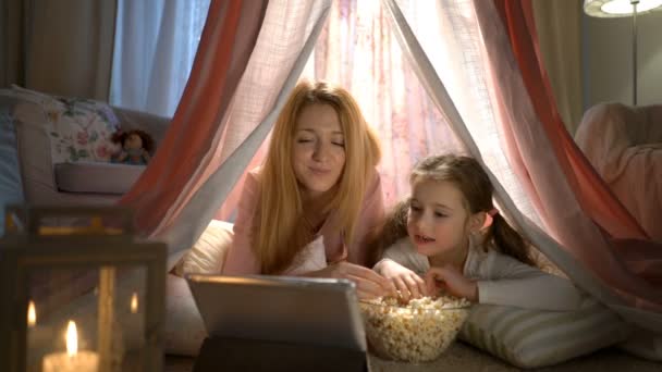 Bambina e sua madre godono guardando cartoni animati online nella tenda nella nursery — Video Stock