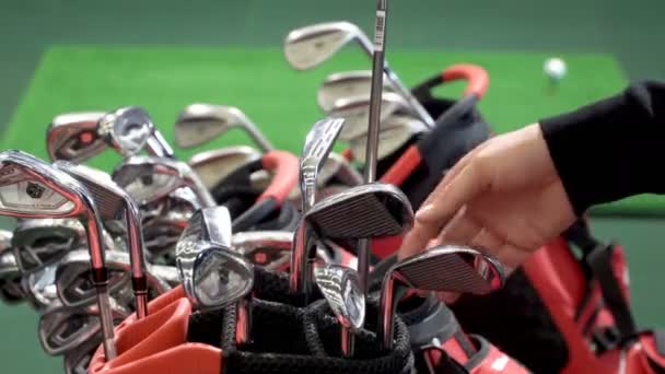 Compradores probando diferentes palos de golf en la tienda de golf . — Vídeos de Stock