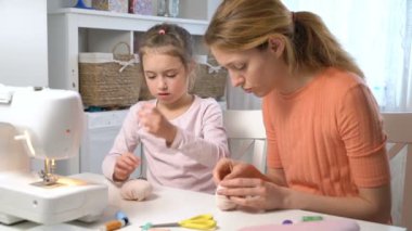 Anne iğne ve iplik kullanarak dikiş küçük kızı öğretiyor
