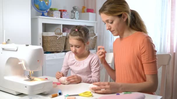 Mom teaching her little daughter to sew using needle and thread — Stock Video