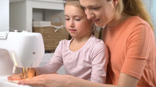 Mutter bringt ihrer kleinen Tochter zu Hause im Kinderzimmer das Nähen mit einer Nähmaschine bei — Stockvideo