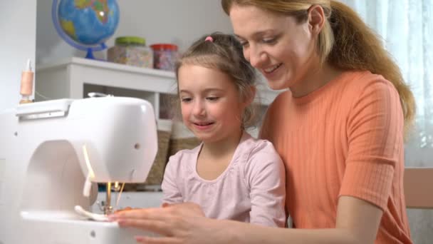 Anne evde kreşte bir dikiş makinesi kullanarak dikiş küçük kızı öğretiyor — Stok video