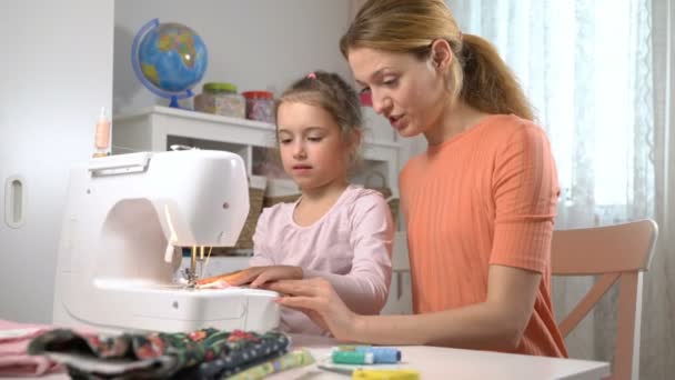 Mamá enseñando a su hija a coser usando una máquina de coser en la guardería en casa — Vídeos de Stock