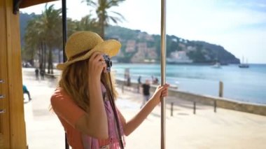 Hasır şapka giyen genç bir kadın, deniz kıyısında eski bir tramvay da ya da trende seyahat etmekten keyif alıyor.