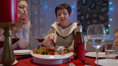 Evde aile Noel yemeği. Büyükannem Noel yemeğinde ailesiyle birlikte fırında hindi pişiriyor. Şarap, mum ve sıcak ev kutlamalarıyla şenlikli bir tatil ortamı..