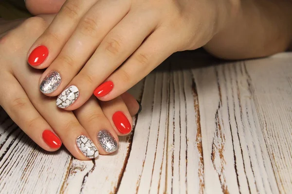 Hands with long artificial manicured nails colored with red nail polish