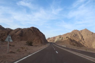 Dağ yolundan. Yatay, kayalar, bulutlar ve güzel asfalt yol ile güneşli gökyüzü