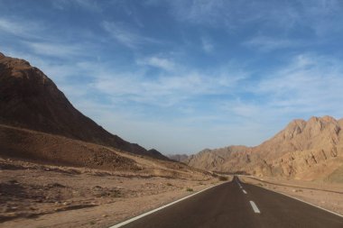 Dağ yolundan. Yatay, kayalar, bulutlar ve güzel asfalt yol ile güneşli gökyüzü