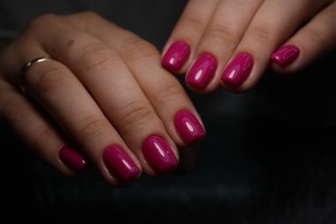 Tırnaklarına manikür yapılan genç bir kadının elleri beyaz arka planda.