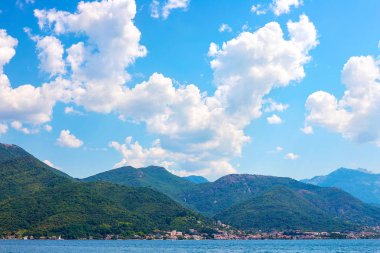 İnanılmaz parlak deniz manzarası. Yeşil ormanlık dağlar ve mavi deniz, mavi gökyüzü ve beyaz bulutlar görünümünü. Boka Kotorska Bay, Karadağ