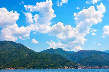 İnanılmaz parlak deniz manzarası. Yeşil ormanlık dağlar ve mavi deniz, mavi gökyüzü ve beyaz bulutlar görünümünü. Boka Kotorska Bay, Karadağ