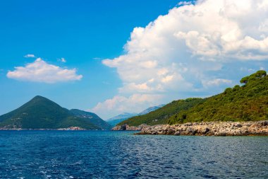 İnanılmaz parlak deniz manzarası. Yeşil ormanlık dağlar ve mavi deniz, mavi gökyüzü ve beyaz bulutlar görünümünü. Boka Kotorska Bay, Karadağ