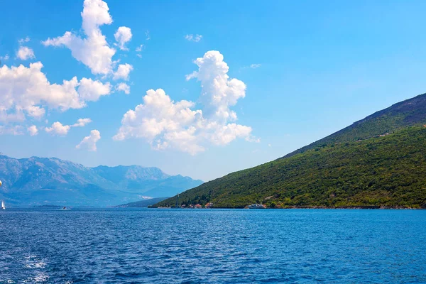 İnanılmaz parlak deniz manzarası. Yeşil ormanlık dağlar ve mavi deniz, mavi gökyüzü ve beyaz bulutlar görünümünü. Boka Kotorska Bay, Karadağ
