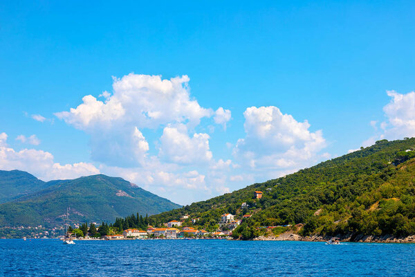 Incredible bright seascape. View of green wooded mountains and blue sea, blue sky and white clouds. Boka Kotorska Bay, Montenegro