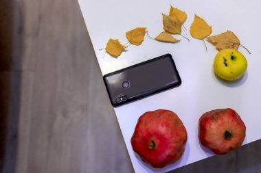 Telefon, smartphone, sonbahar yaprakları ve taze meyve, arasında masadaki yalan görüntülemek yukarıdan