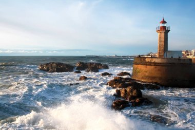 Deniz manzarası. Dalgalar deniz fenerini günbatımında taşlara karşı Atlantik Okyanusu kaza. Lisbon, Portekiz