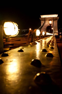 Soyut kentsel gece manzarası. Yaktı gece, fenerler ve yaya bir bölümü, arka köprü görünümünü, odak dışında bulanık. Budapeşte, Landhide Köprüsü, Macaristan