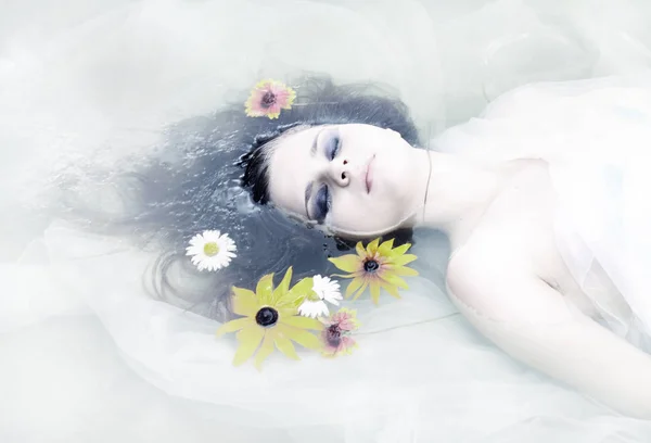 一个黑头发的女孩在水里穿白衣服 闭着眼睛躺在水里的肖像 — 图库照片