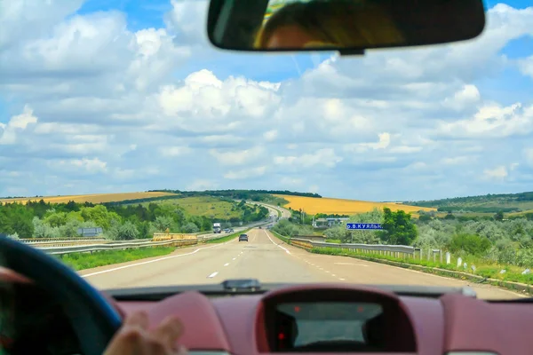 The dashboard of the car, the view of the beautiful landscape and the road through the glass of the car