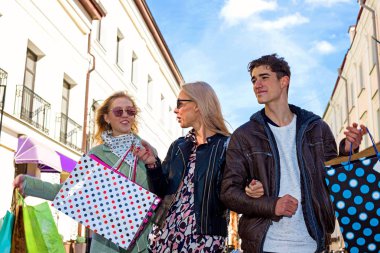Tüketim ve satın alma gücü sembolü olarak birçok alışveriş çantası ile üç kadın