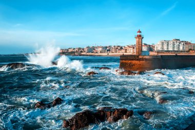 Atlantik Okyanusu 'nun dalgaları gün batımında deniz fenerinin yanındaki kayalara çarpar.