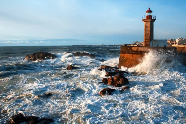 Atlantik Okyanusu 'nun dalgaları gün batımında deniz fenerinin yanındaki kayalara çarpar.