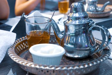 Su ısıtıcısı ile bakır bir tabak üzerinde bir bardak nane ve şeker ile Fas çayı