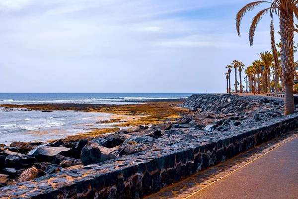 Siyah bir plajda küçük taşlar, arka planda akean dalgalar ve bir sörfçü vardır — Stok fotoğraf