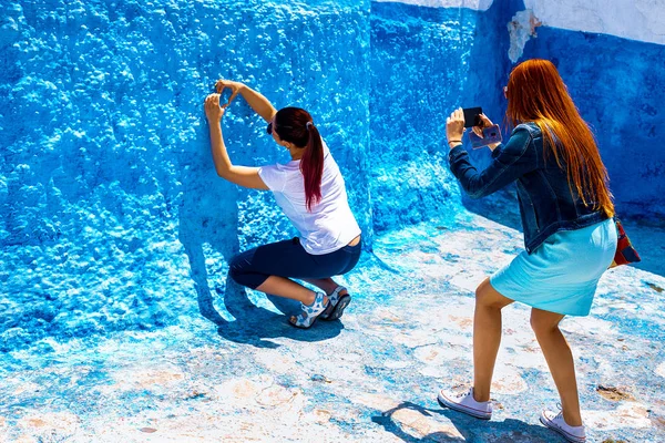 Duas jovens são fotografadas contra a parede azul em Rabat, Marrocos. A famosa cidade pitoresca azul e branca . — Fotografia de Stock