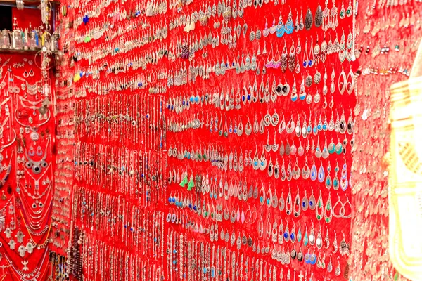 Fas'ta piyasada kırmızı bir arka plan üzerinde küpe, takı bir seçim.