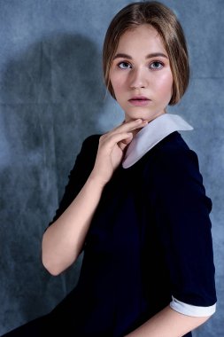 Gri arka planda izole sarı saçlı güzel bir yalnız kız dramatik portre