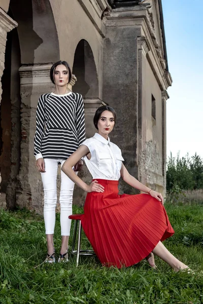 Открытый модный портрет двух молодых красивых женщин в модной одежде, позирующих на улице — стоковое фото