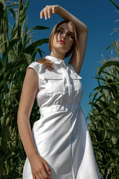 Portrét světlovlasé dívky v módních a stylových šatech, mezi listím kukuřičného pole. — Stock fotografie