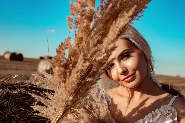 Portrait of a beautiful girl, blonde with long hair in a field a sunny day at sunset. — Stock Photo, Image