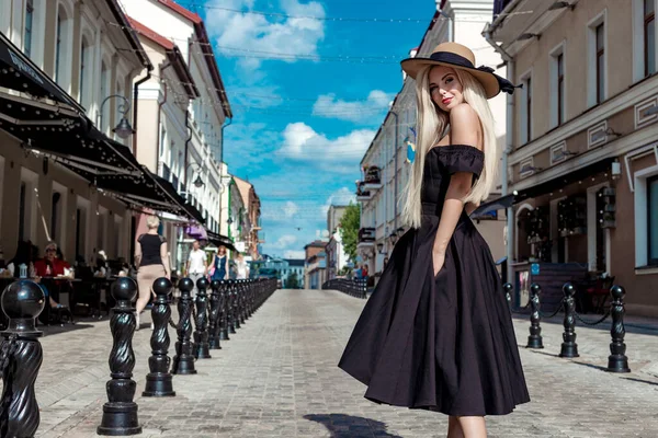 Высокая мода портрет грациозной женщины в элегантной соломенной шляпе и платье, которое ходит по улице города — стоковое фото