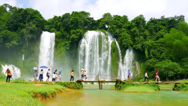 Ban Gioc Waterfall - I visitatori attraversano il ponte di legno vicino alla cascata. Vietnam. Risoluzione 4K — Video Stock