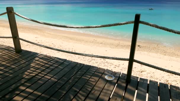 Vue sur la plage de l'île tropicale avec ombres à feuilles de palmier sur pont en bois. Résolution 4K — Video