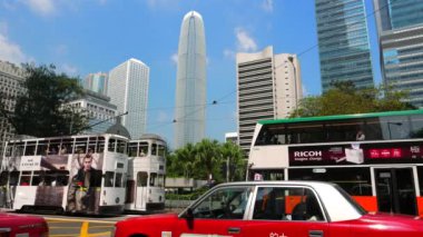 HONG KONG - Trafik ve çift katlı tramvaylarla şehir merkezinde karşıdan karşıya geçen insanlar. 4K çözünürlüğü.