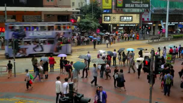 HONG KONG - Tráfico urbano con tranvía de dos pisos y personas con paraguas cruzando la calle en días de lluvia. Velocidad de resolución 4K . — Vídeos de Stock