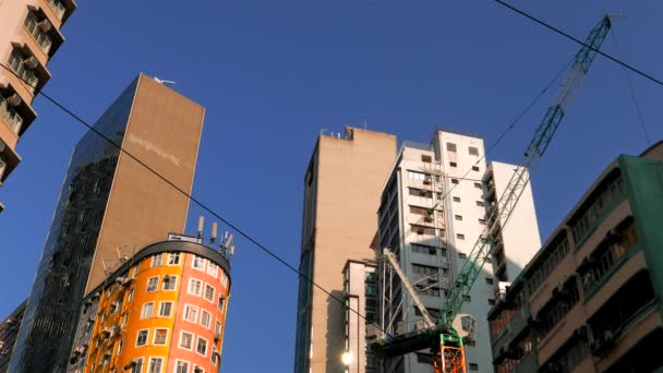 Gru con alti edifici in luce serale contro il cielo blu. Hong Kong 2015. Risoluzione 4K. — Video Stock