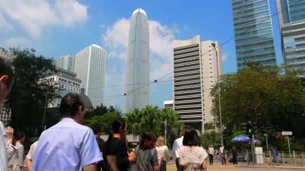 HONG KONG - październik 2015: Ludzie przechodzący przez ulicę w centrum miasta z drapaczami chmur w tle. Rozdzielczość 4K. — Wideo stockowe